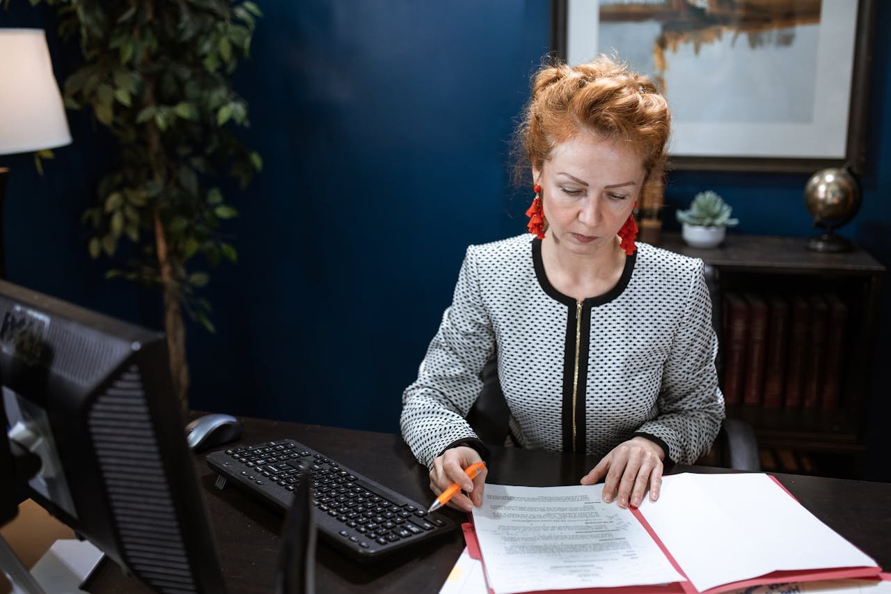 A focused woman working on paperwork in a modern office environment.